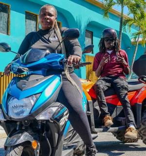 a man sitting on a motorcycle with a man wearing a mask