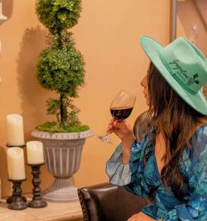 一位戴着帽子、手捧一杯葡萄酒的女士