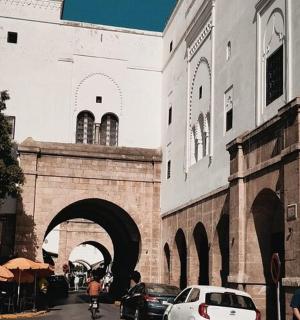 a building with an archway and cars parked on a street