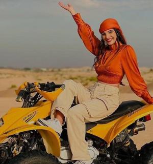 一名女子在沙漠中骑着四轮摩托车