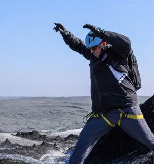 muž stojící na skále s rukama ve vzduchu