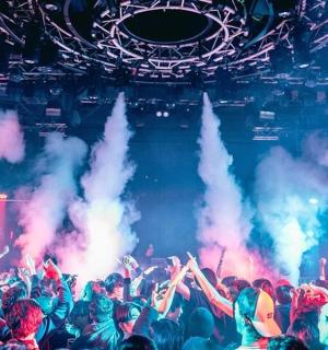 a crowd of people at a concert with smoke