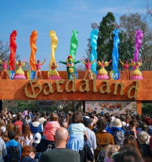a crowd of people watching a parade with performers on top