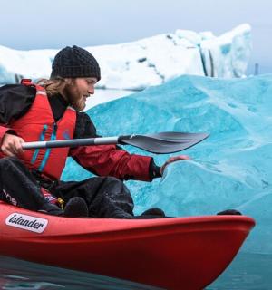 a man in a kayak in front of an iceberg