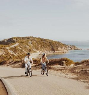 dva lidé jedoucí na kolech po silnici u oceánu