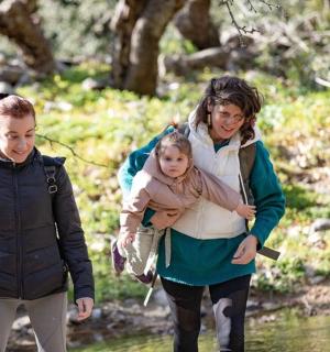 dvě ženy a dítě procházející potokem