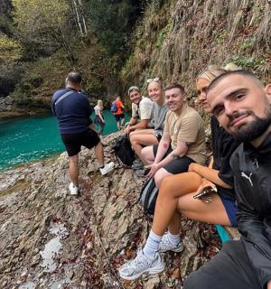 一群人坐在河边的一块岩石上