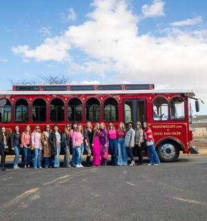 skupina lidí stojících před červeným autobusem