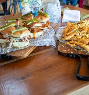 木桌上放着两个三明治和炸薯条