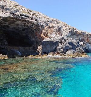a cave in the water next to a cliff