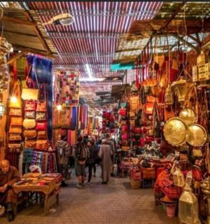 a group of people walking through a market with shops