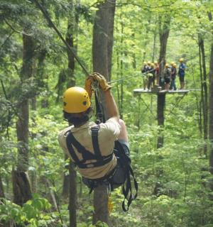 一名男子正悬挂在森林里的滑索上