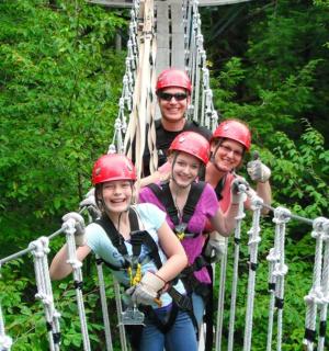 a group of people on a suspension bridge in the forest