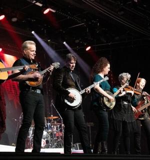 skupina lidí na pódiu hrajících na hudební nástroje