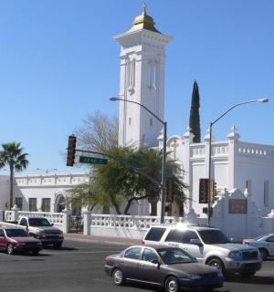 一栋带有钟楼的白色大楼，街道上有汽车