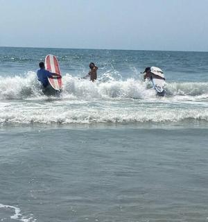 tři lidé v oceánu se surfovými prkny ve vlnách