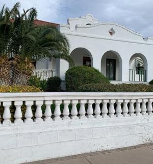 一座有白色篱笆和棕榈树的白色房子