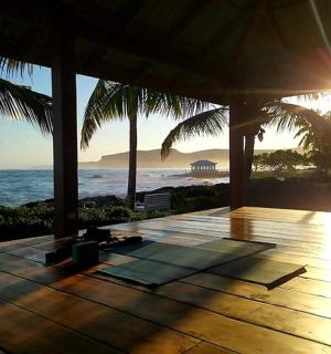 a wooden deck with the sun setting over the ocean