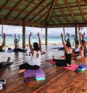 a group of people doing yoga on the beach