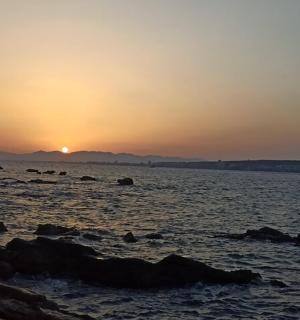 ein Sonnenuntergang an einem Strand mit Felsen im Wasser