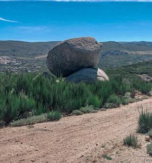 a rock sitting on the side of a dirt road