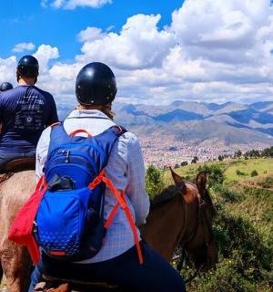 two people riding on a horse on a hill