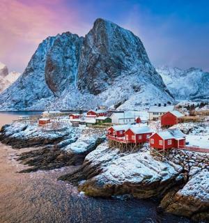 a village on a rocky island with snow covered mountains