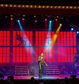 一个男人站在舞台上，舞台上有红色和蓝色的灯光