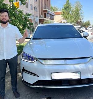 一名男子站在一辆白色汽车旁边