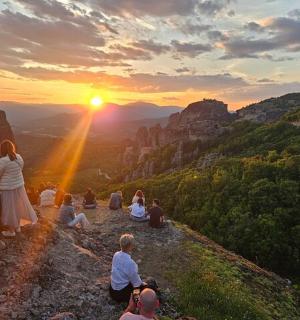 a group of people sitting on a mountain watching the sunset