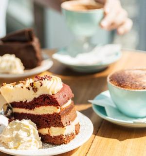 a table with a piece of cake and a cup of coffee