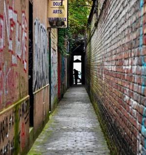 an alley with graffiti on the side of a brick wall
