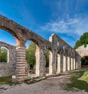 an old stone building with arches in a field