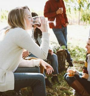 一群人中,一位女士正在喝一杯葡萄酒