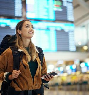 a woman standing in an airport holding a cell phone