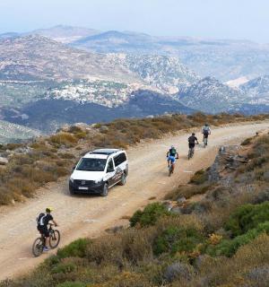 a group of people riding bikes and a car on a dirt road