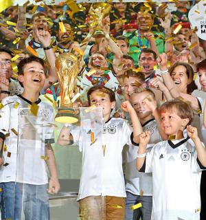 a group of children holding up the soccer league trophy