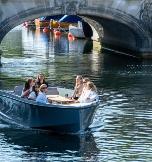 a group of people in a boat on the water near a bridge