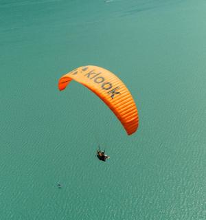 一个人骑着风筝在水面上空飞行