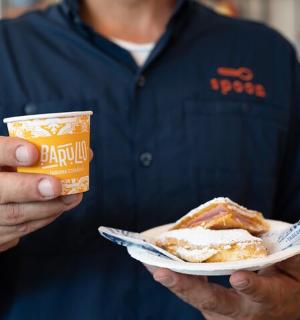 一名男子拿着盘子，盘子里装着一块蛋糕和一杯饮料