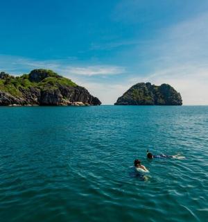 two people swimming in the water near two islands