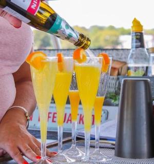 žena nalévá pomerančový džus do čtyř sklenic na šampaňské