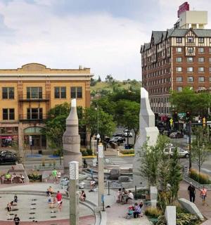 a group of people standing around a fountain in a city