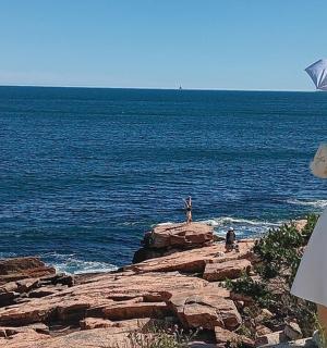 一位身穿白色连衣裙的女子在海边撑着伞