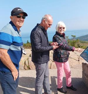 两名男子和一名女子站在标志牌旁边