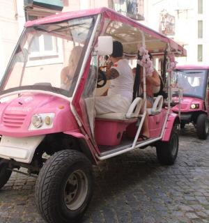 two people riding a pink golf cart on a street