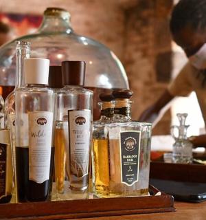 egy asztal alkoholos üvegekkel és egy maszkot viselő nővel