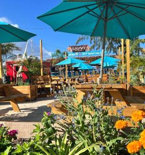 egy terasz asztalokkal, napernyőkkel és virágokkal