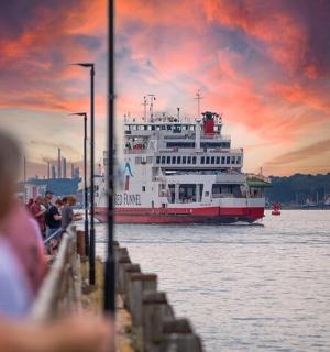 a ferry boat on the water with a sunset