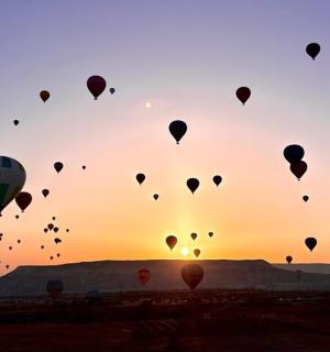 a bunch of hot air balloons in the sky at sunset